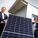 Der REWAG-Vorstandsvorsitzende Torsten Briegel und Oberbürgermeisterin Gertrud Maltz-Schwarzfischer mit einem Solar-Modul vor der neuen PV-Anlage.