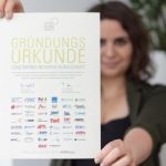 Eine Frau hält die Gründungsurkunde der Stadtwerke-Initiative Klimaschutz ins Bild.