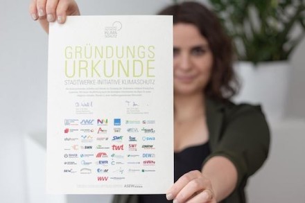 Eine Frau hält die Gründungsurkunde der Stadtwerke-Initiative Klimaschutz ins Bild.