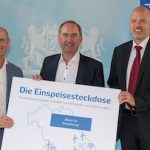 Bayernwerk-Vorstandsvorsitzender Egon Leo Westphal (rechts) und LEW-Vorstand Christian Barr (links) stellen dem bayerischen Wirtschaftsminister Hubert Aiwanger die Einspeisesteckdose vor.