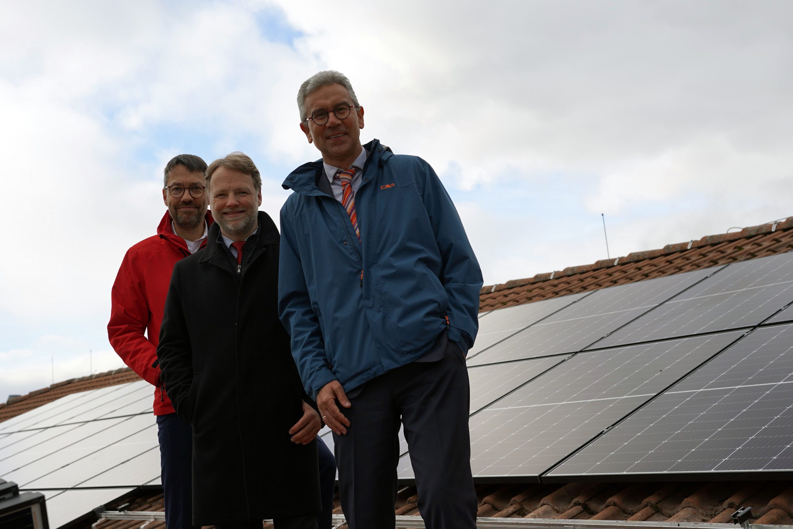 Das Bild zeigt enercity-Vorstand Marc Hansmann; Finanzminister Gerald Heere; Justizstaatssekretär Thomas Smollich, auf dem Dach der Justizvollzugsanstalt Sehnde. Im Hintergrund sind PV-Module zu sehen.