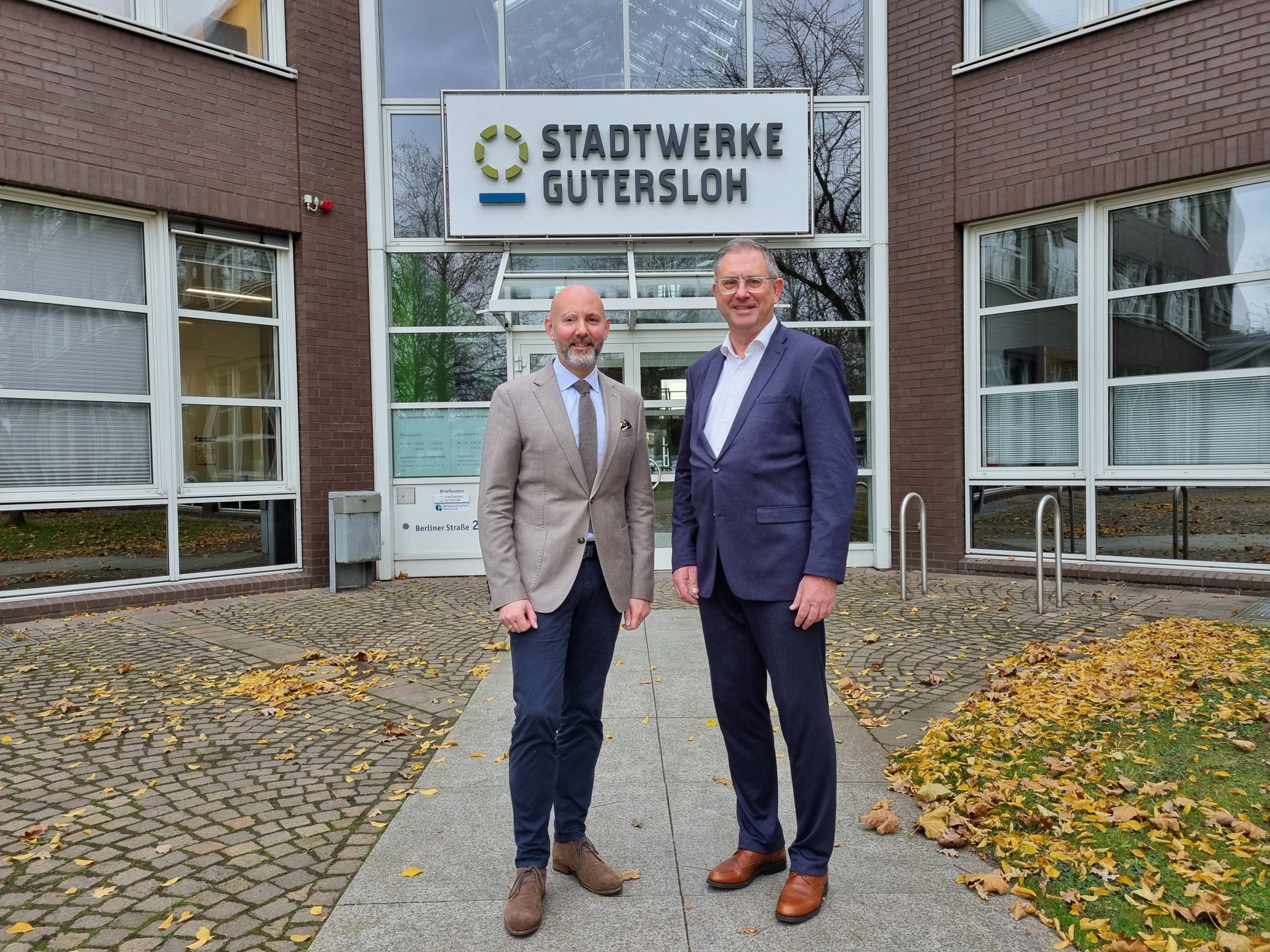 Das Bild zeigt den SWG-Aufsichtsratsvorsitzenden Henning Matthes und den künftigen neuen Geschäftsführer der Stadtwerke Gütersloh, Dietmar Spohn. Im Hintergrund ist der Schriftzug Stadtwerke Gütersloh zu lesen.